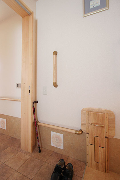 折りたたみができる玄関のベンチと、立ち上がりと移動の動作を補助するために施工した手すり