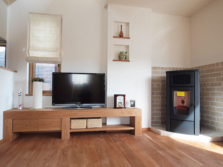 リビングのアップ。木目のきれいなテレビラックに、モダンなイタリア製ペレットストーブが似合っている
