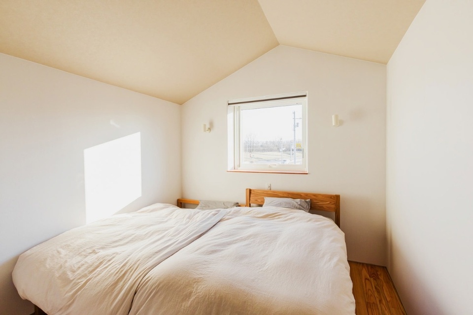元の家の屋根を利用したという天井の形がユニークな2階の寝室
