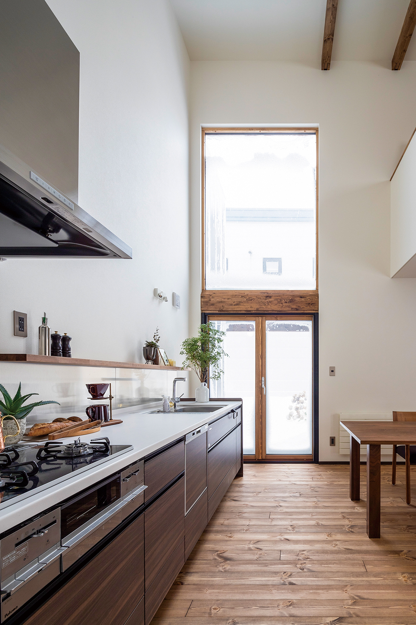 リビングに隣接するキッチン・ダイニングは、壁付けキッチンと光を大きく取り入れられる吹抜けの窓がポイント