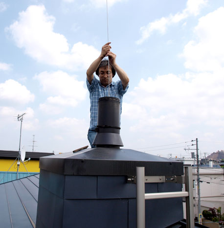 ブラシの先に少しずつ棒を足していき、こすりおとす。「落ちたかー?」とOさんが声をかけると、煙突の中から「いっぱい落ちてきた!」という奥様の声が。