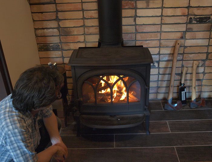 薪ストーブに火を入れるOさん。空気の量の調節がまだうまくいかないそう。