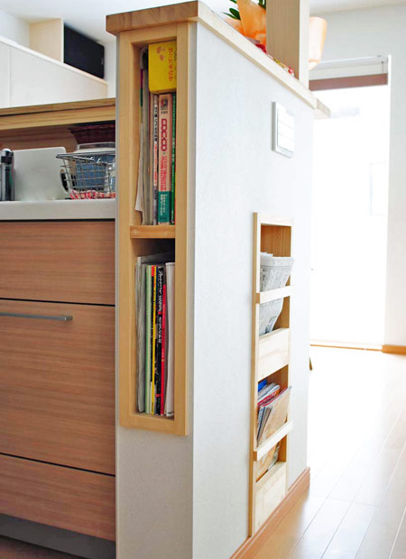 キッチンカウンター隣の壁をくり抜いて料理本を入れる棚にした。脇はマガジンラック